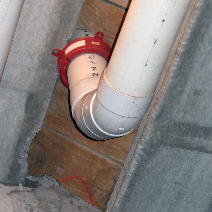 An incorrectly installed fire collar. The collar should be fixed directly to the underside of the concrete floor slab.